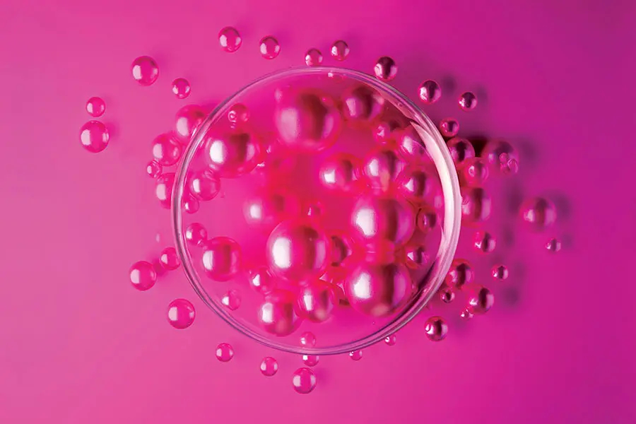 Pink microbeads in a petri dish and spilling out.